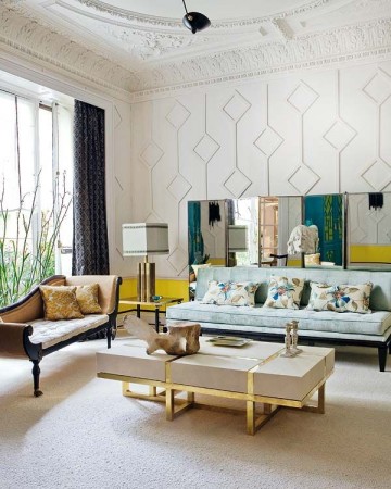 A living room with white furniture and gold accents designed by Jacques Grange.