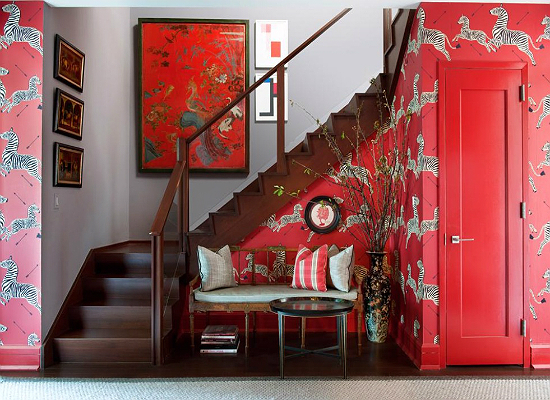A stunning foyer with red wallpaper and a bench.