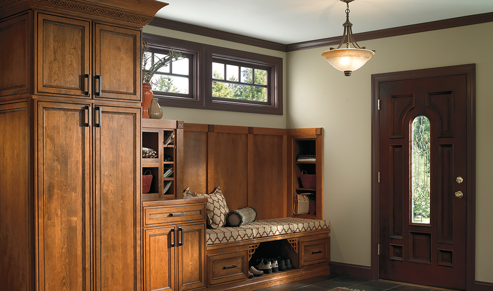 A wooden bench in a mudroom with cabinets.
