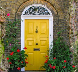 A yellow front door with red flowers on it.