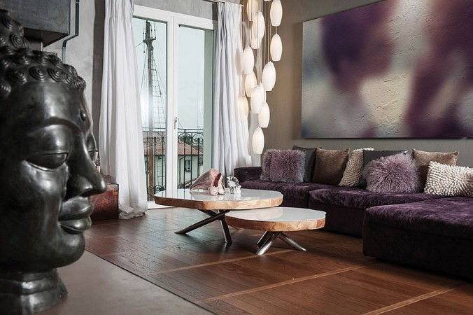 A living room with a purple couch and a buddha statue featuring interior features that bring nature home.