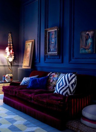 A living room with dark blue walls and a red couch.