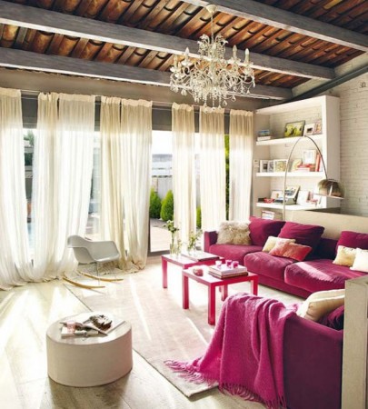 A living room with chic pink couches and a stylish chandelier.