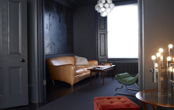 A moody living room featuring dark walls and a leather couch.