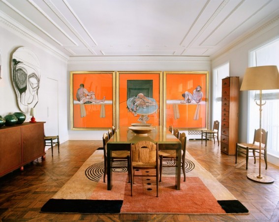 A dining room with orange paintings on the wall showcasing designer focus.