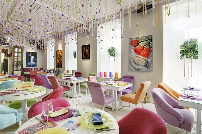 A restaurant with vibrant chairs and tables.