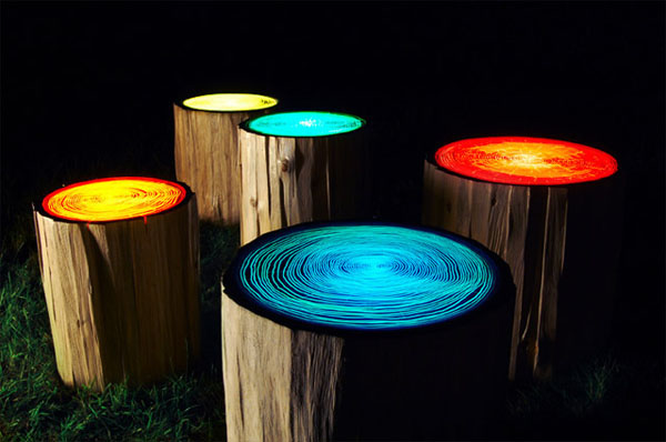 A group of wooden stumps adorned with colored lights, bringing nature home.