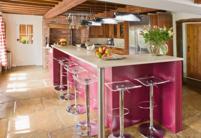 A kitchen with a pink island and 18 stylish bar stools.