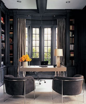 A dark and moody home office with black walls and chairs.