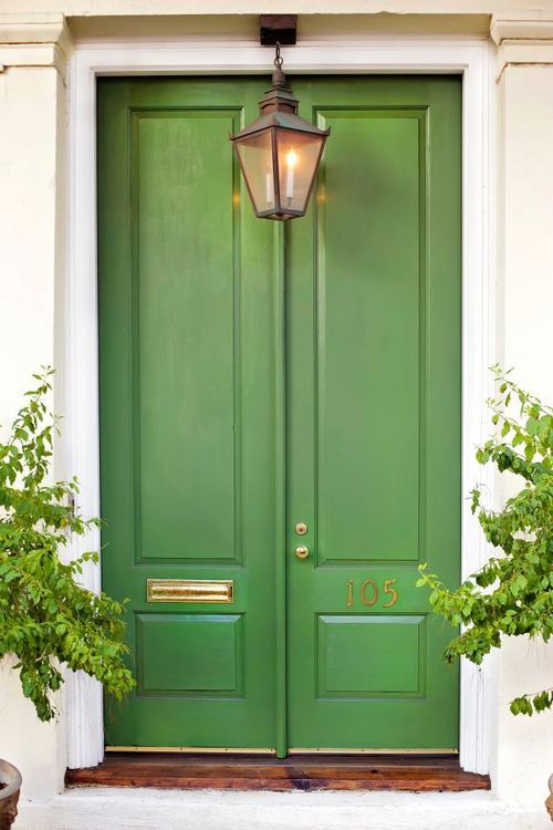 A green front door with a potted plant on it, showcasing an eye-catching front door paint color.