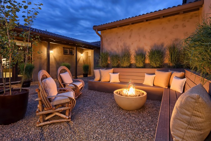 A backyard patio with wicker furniture and a fire pit.