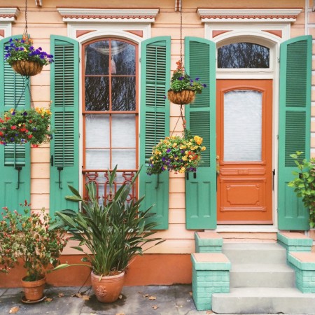 A Mardi Gras tribute in New Orleans: a house with green shutters and potted plants.