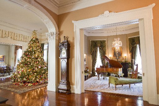 A festive living room adorned with a New Orleans-inspired Mardi Gras tribute including a Christmas tree and piano.