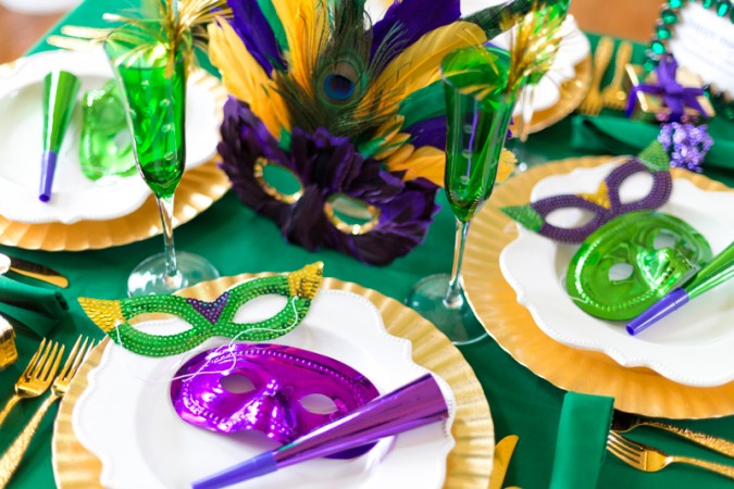 Tribute to New Orleans with gold and green Mardi Gras table setting decorations.