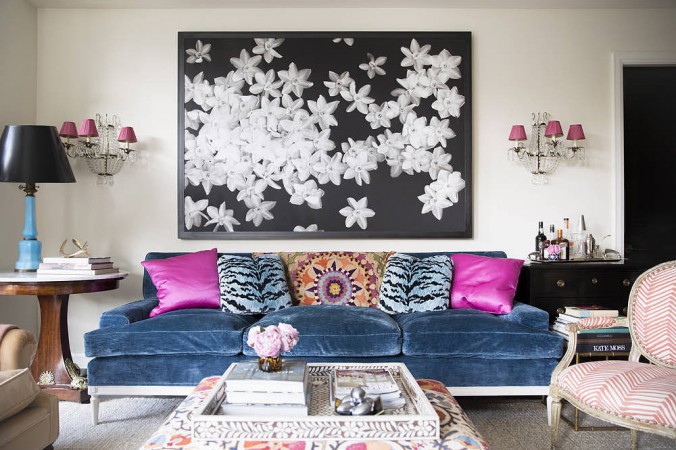 A fashionable living room with a blue couch and pink pillows.