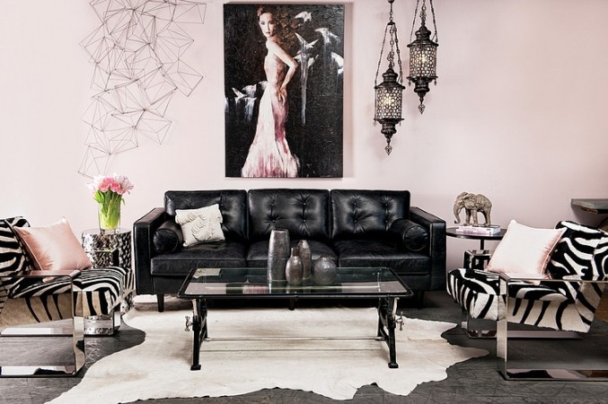 A fashionable living room with black leather furniture and zebra print rugs.