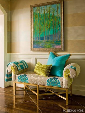 A charming bench and colorful artwork welcome in this foyer 