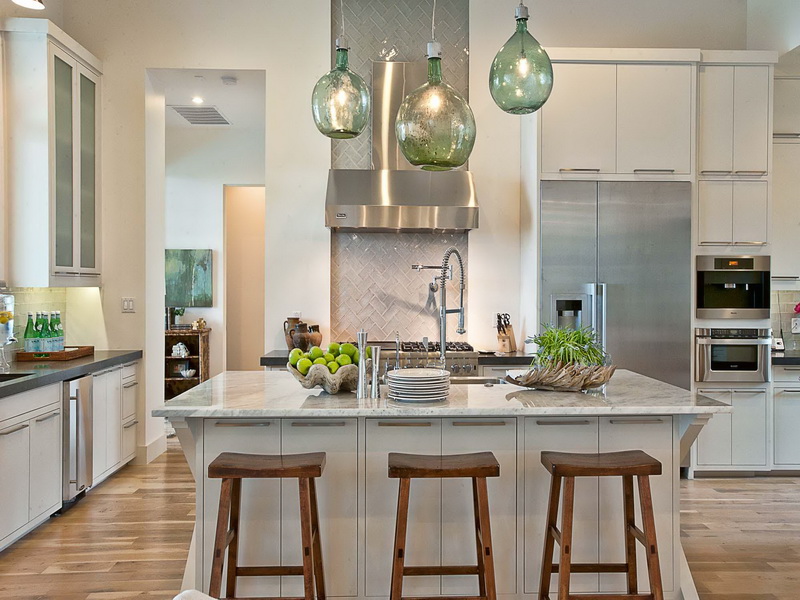 A kitchen with a center island and stools transformed by beautiful pendant lights.