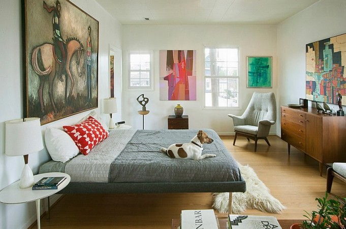 A bedroom showcasing abstract art with a bed and a dog laying on top of it.