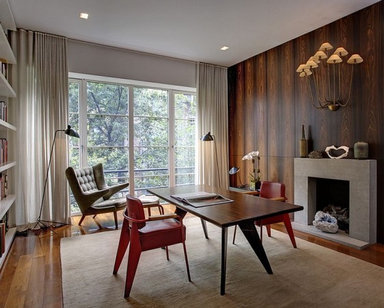 A Mid-Century Modern home office with wood paneling and a fireplace.
