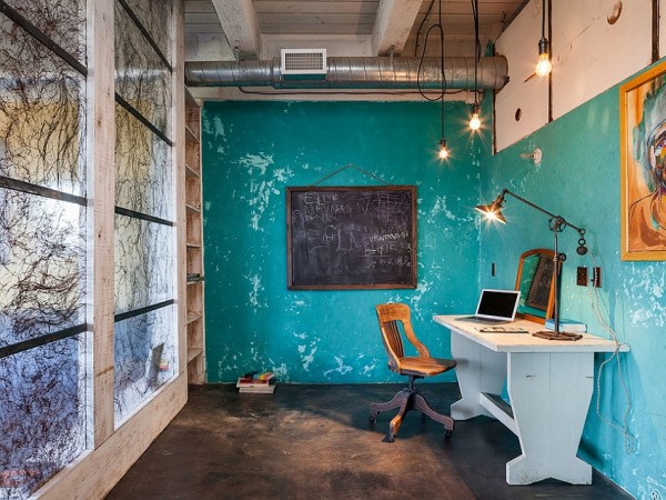 A home office with an industrial style desk and a chalkboard.