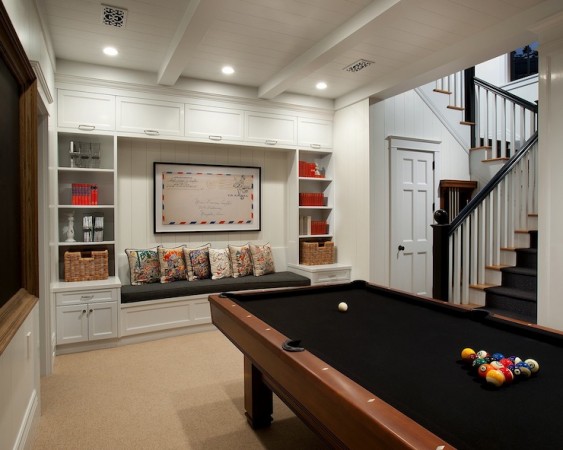 A basement transformed into a game room featuring a pool table and bookshelves.