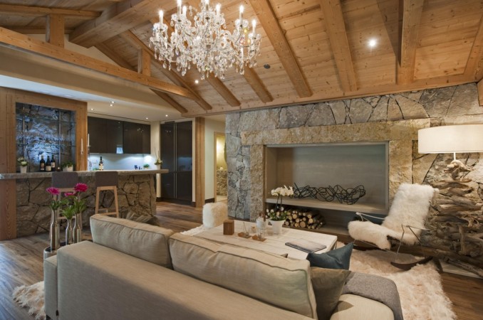 A living room with stone walls and a chandelier in a modern home.