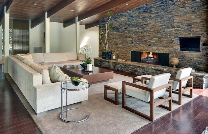 A modern living room with stone walls and a fireplace in a wood and stone modern home.