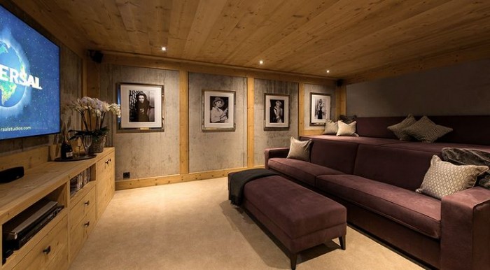 A creative use for the basement: A home theater room with a purple couch and tv.