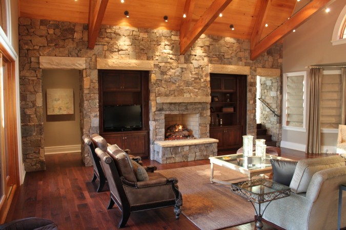 A living room in The Wood and Stone Modern Home with a stone fireplace.