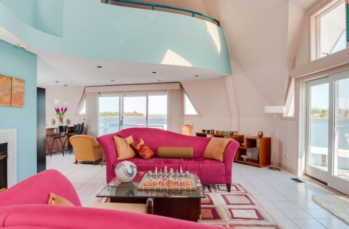 A living room with sophisticated pink couches and a view of the water.