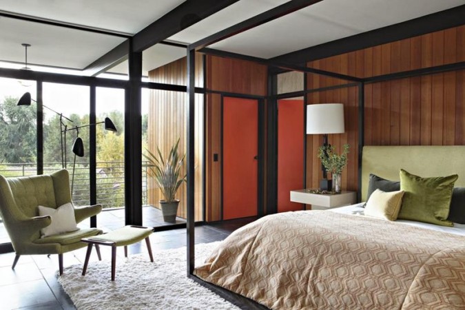 A Mid-Century modern bedroom with wooden walls and a green chair.