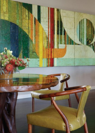 A wooden table and chairs in a dining room, incorporating abstract art.