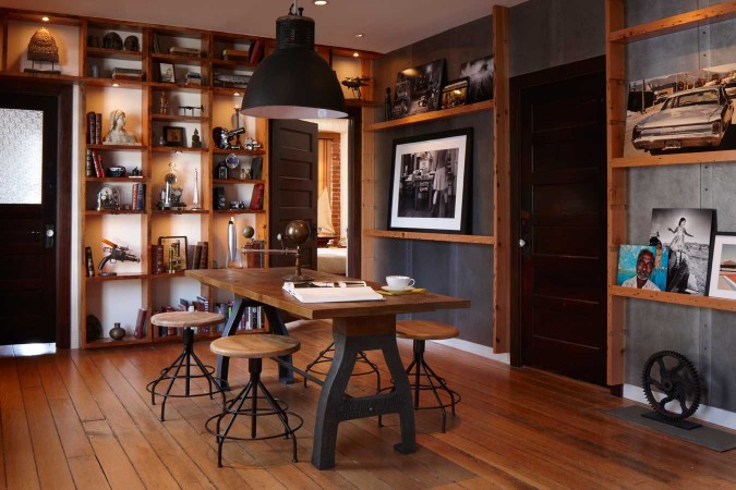 A room with a wooden table and bookshelves in an industrial style home office.