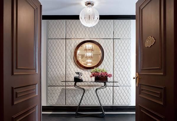 A hallway with upholstered walls and a mirror for sophisticated glamour.