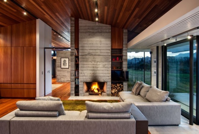 A modern living room with wood ceilings and a fireplace in The Wood and Stone Modern Home.