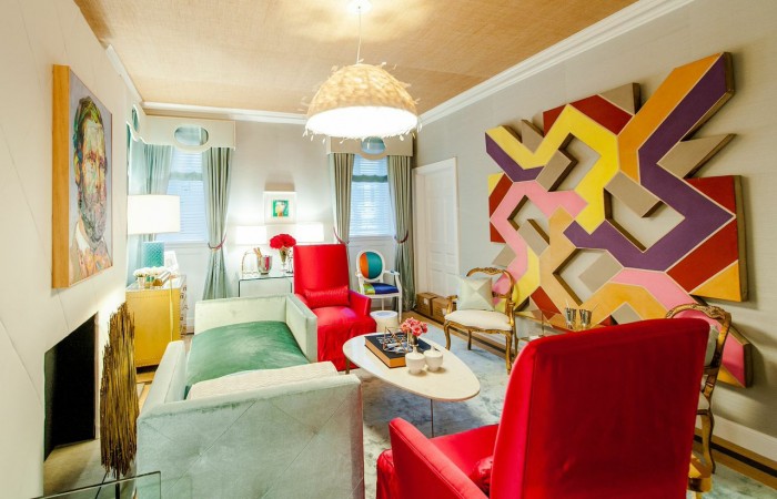 A living room with colorful chairs and a painting on the wall at a Designer Showhouse.