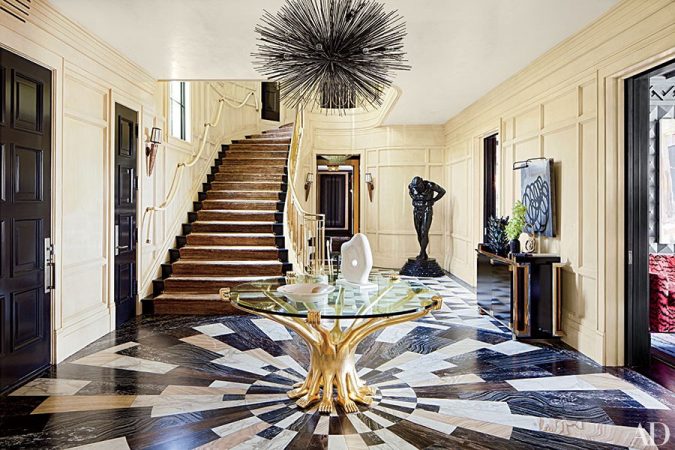 A sculptural black and white foyer with a stunning staircase and an exquisite chandelier.