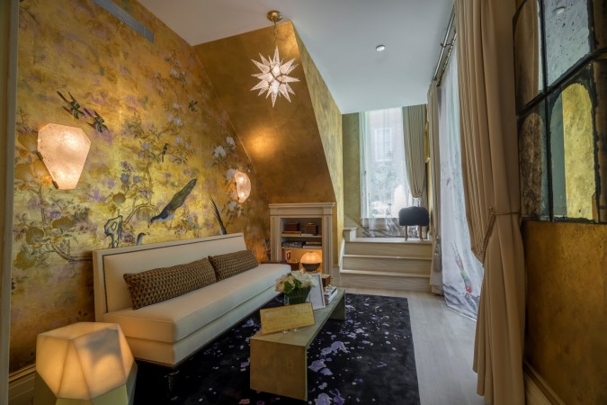 A living room with gold walls and a fireplace featured in 20 Designer Showhouse Rooms to Spark Your Inner Decorator.