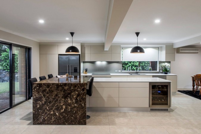 A modern kitchen with marble waterfall counter tops and stainless steel appliances.