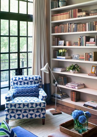 A cozy living room with blue chair and bookshelves.