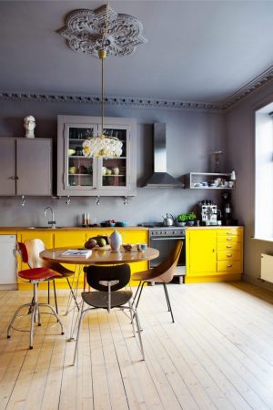 A modern kitchen with a yellow table and chairs, adding color and character.