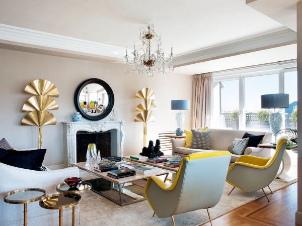 A living room with sculptural yellow chairs and a chandelier.