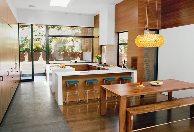 A kitchen with a table and chairs featuring waterfall kitchen countertops.