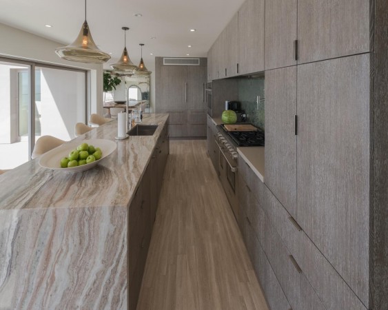 A modern kitchen with marble waterfall countertops and wooden cabinets.
