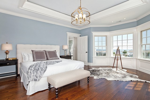 A coastal bedroom with blue walls and hardwood floors.
