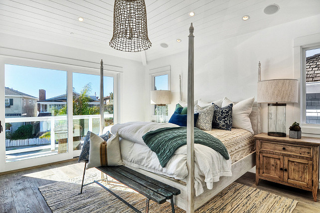 A coastal bedroom with a four poster bed and a sliding glass door.