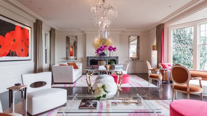 A living room with pink furniture and a chandelier showcased in 20 Designer Showhouse Rooms.