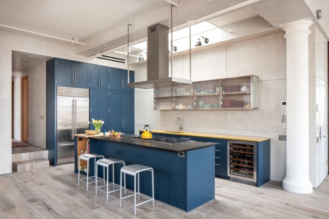 A modern kitchen with vibrant blue cabinets and warm wooden floors.