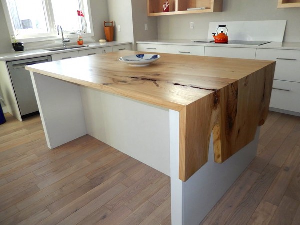 A kitchen island with a wooden top and waterfall kitchen countertops.